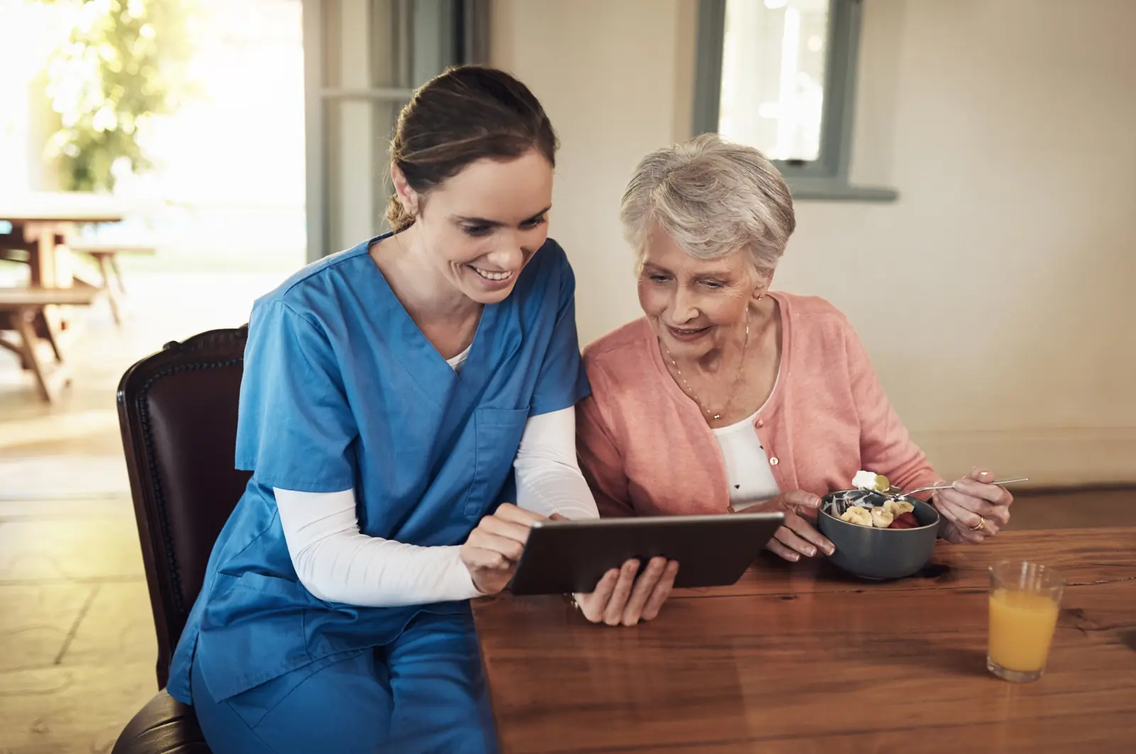 Home health nurse reviewing a care plan on a tablet with a senior woman