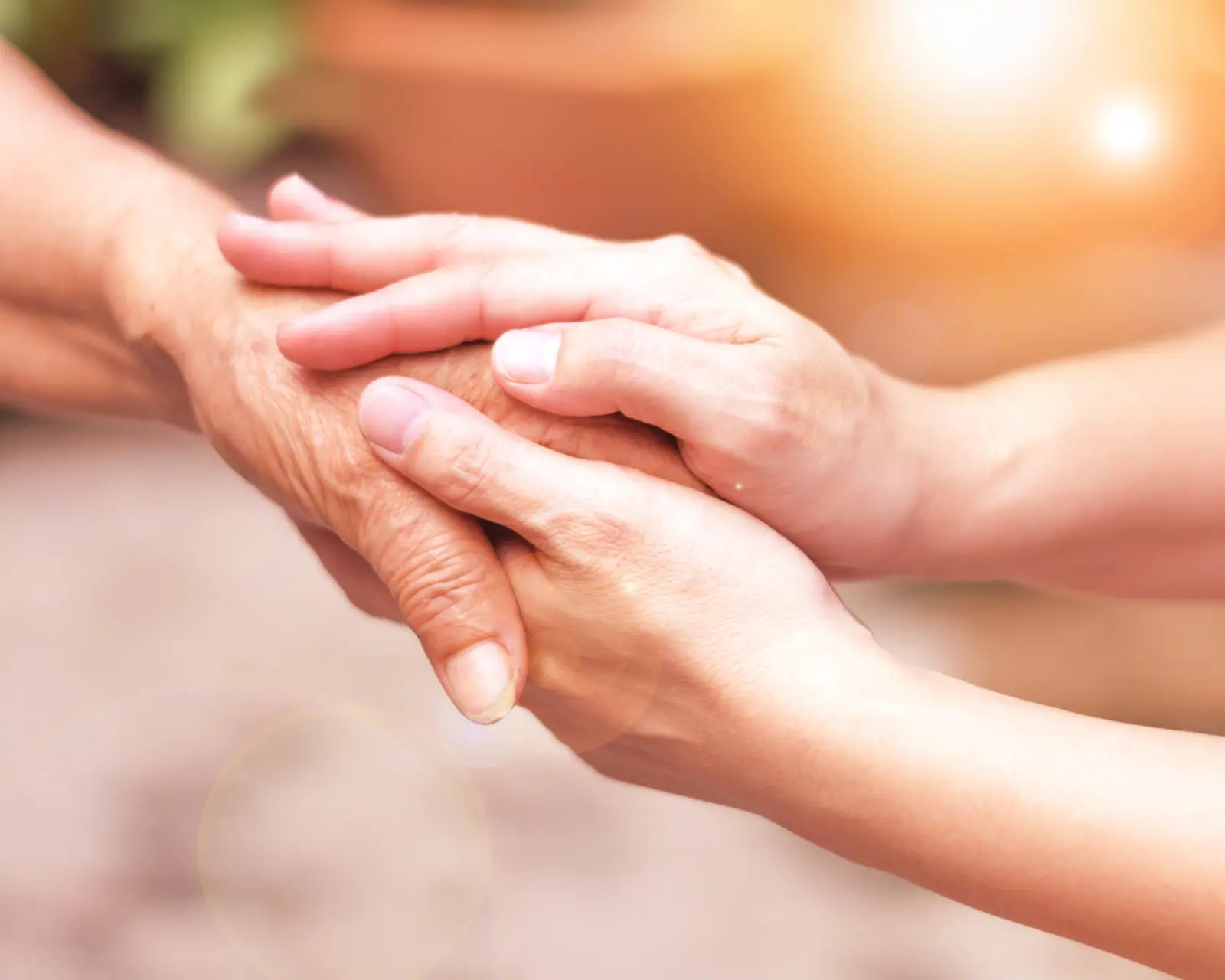 Two hands held together in comfort during palliative care at home