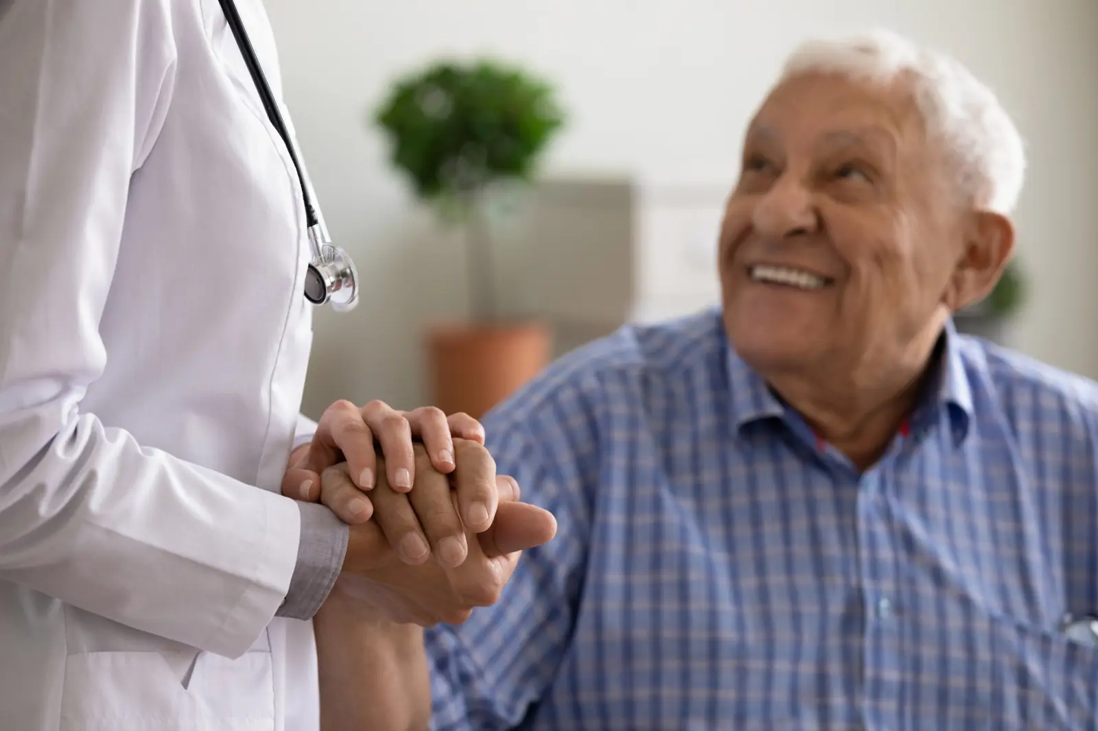Nurse holding the hand of a smiling senior man